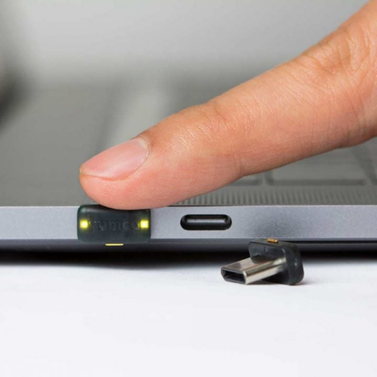 YubiKey 5C Nano FIPS (140-3) в порту USB-C ноутбука, палець торкається кнопки